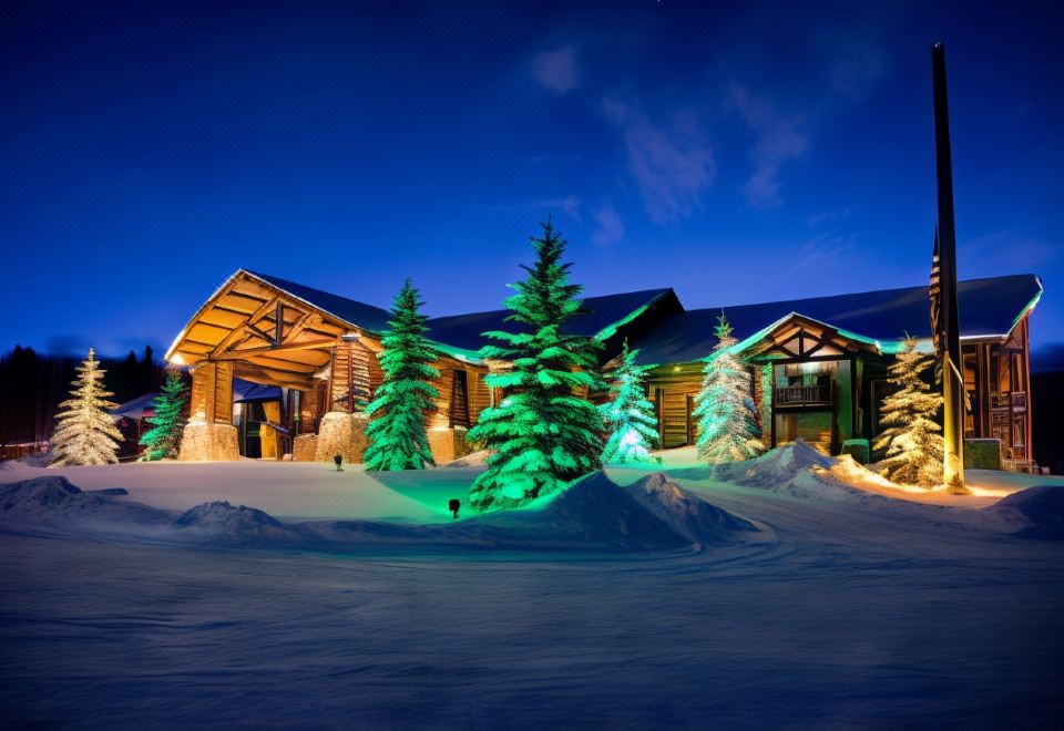 a large wooden building surrounded by snow , with a christmas tree in front of it at Daniels Summit Lodge