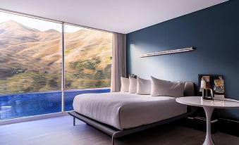 a modern bedroom with a large window overlooking a mountain , featuring a bed with white linens and a blue wall at Marriott Maracay Golf Resort