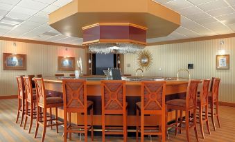 a modern bar with a wooden counter and several chairs surrounding it , creating a cozy atmosphere at DoubleTree by Hilton Hotel Oak Ridge-Knoxville