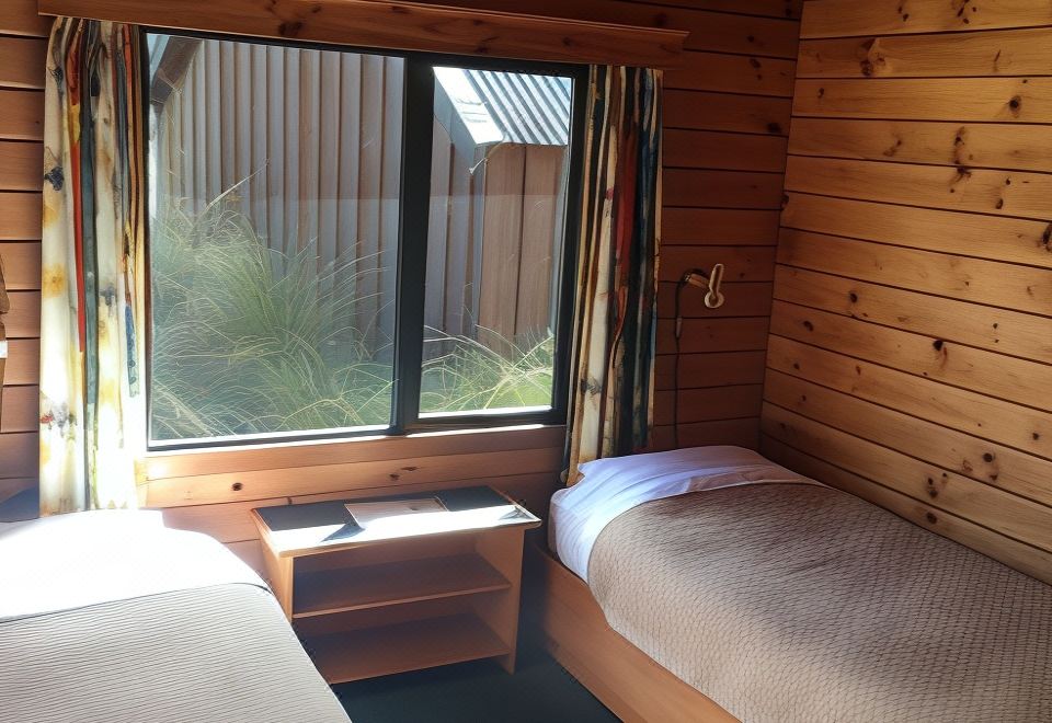 a cozy wooden cabin bedroom with two beds , a window , and a desk , giving a cozy and inviting atmosphere at Alpine Lodge