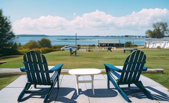 two green lawn chairs are placed on a deck with a view of the ocean at Friars Bay Inn & Cottages