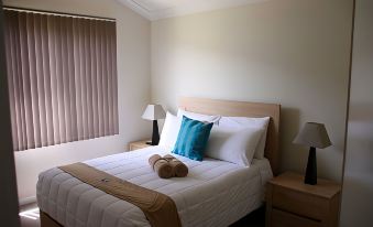 a neatly made bed with a white comforter and two blue pillows is shown in a bedroom at Seaspray Beach Holiday Park