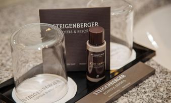a promotional advertisement for steigerberger hotels & resorts features a glass with a brown label and other items in front at Steigenberger Airport Hotel Berlin