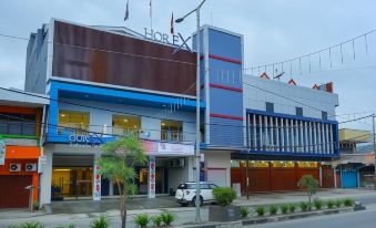 a large building with a red and blue facade is on the corner of a street at Horison Express Sentani