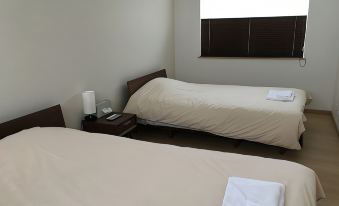 a hotel room with two beds , each topped with white towels and placed next to a window at Ume
