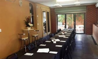 a long dining table with black tablecloths and chairs , set up for a formal event at Seymours on Lydiard