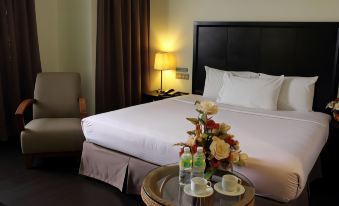 a hotel room with a king - sized bed , a small table with two cups and a vase of flowers , and a window with curtains at Good Hope Hotel