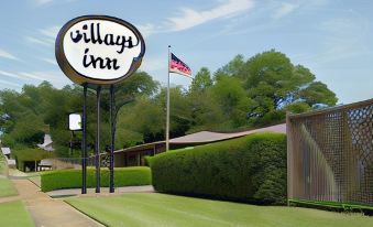 a sign for the village inn with a green lawn and trees in the background at Village Inn