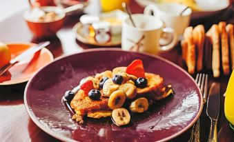 a plate of french toast topped with fruit and bananas , sitting on a dining table at Banchory Lodge Hotel