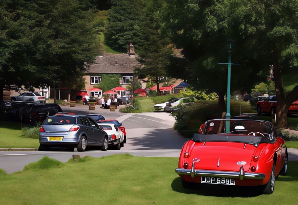 a red car is parked in the middle of a grassy area , surrounded by other cars and trees at The Lamb Inn