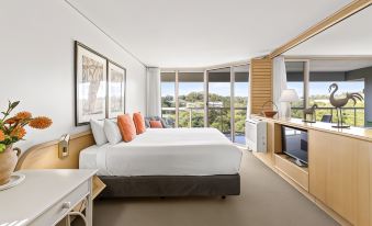 a modern hotel room with a large bed , white bedding , and a view of the city at Pacific Bay Resort