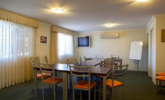 a conference room with a table surrounded by chairs and a television mounted on the wall at Mandarin Motel