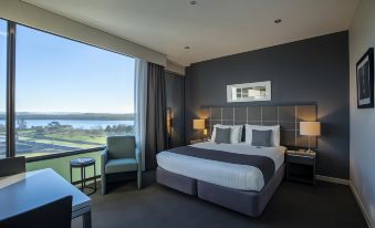 a modern hotel room with a large window offering a view of a golf course , a bed , and two chairs at Quest Highbrook