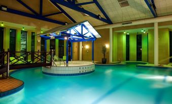 a large indoor pool with a blue and white tiled floor , surrounded by lounge chairs at Gloucester Robinswood Hotel, BW Signature Collection