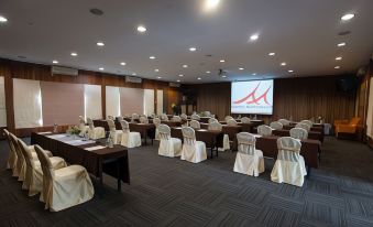 a large conference room with rows of chairs arranged in a semicircle , and a projector screen mounted on the wall at Baan Amphawa Resort & Spa