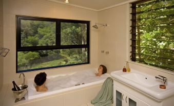 a man and a woman are relaxing in a bathtub with a window view , enjoying each other 's company at Whispering Valley Cottage Retreat