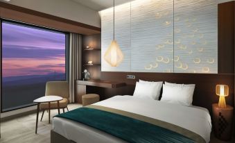 a hotel room with a large bed , a desk , a chair , and a window overlooking the ocean at Hotel Metropolitan Akita