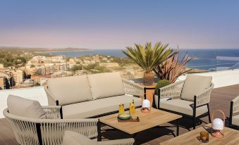 a modern outdoor living area with a view of the ocean , featuring comfortable seating and a wooden coffee table at H10 Imperial Tarraco