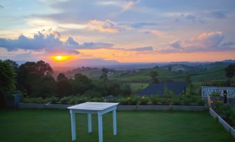 a white table is placed in a grassy area with a beautiful sunset in the background at Veravian Resort
