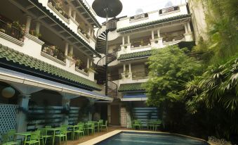 a courtyard with a pool surrounded by green chairs and tables , as well as a spiral staircase leading to the entrance at Hotel Galleria
