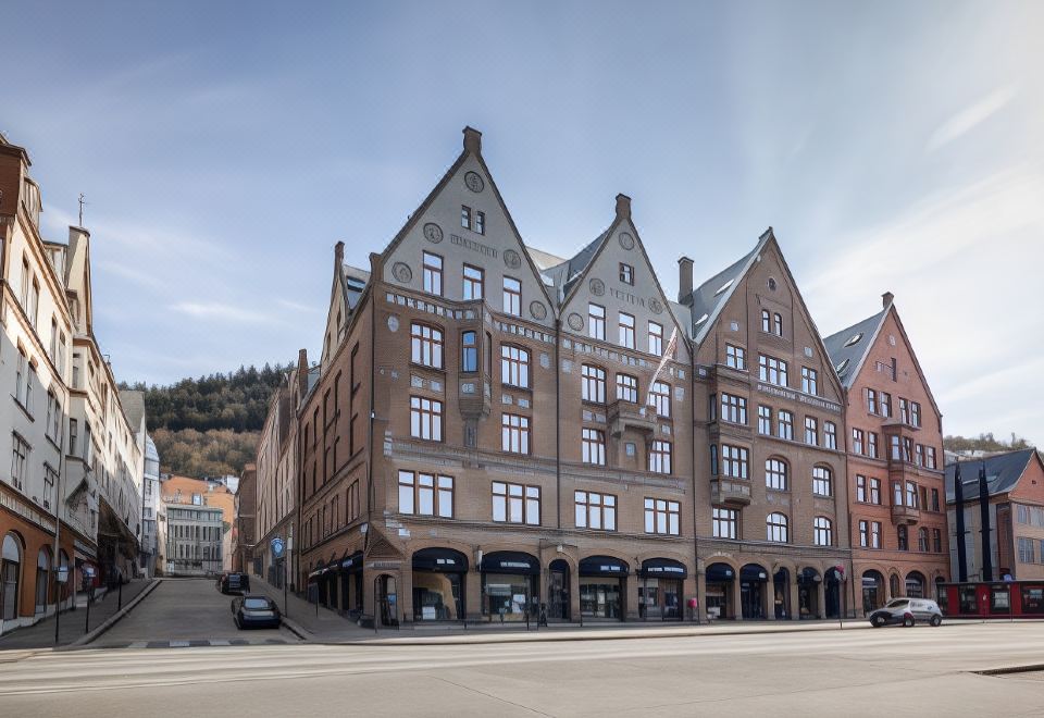 a grand european - style building with multiple floors , ornate roof details , and a tiled facade , situated on a cobblestone street at Clarion Hotel Bergen
