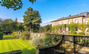 a large house with a pool and garden is seen in the background , surrounded by greenery at Doxford Hall Hotel and Spa