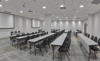 a large conference room with multiple rows of chairs arranged in a semicircle , providing seating for a large group of people at JL Hotel by Bourbon