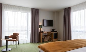 a hotel room with a bed , desk , and window curtains , along with a chair and tv at Best Western Plus Hotel Amstelveen