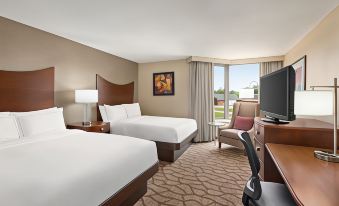 a modern hotel room with two beds , a desk , and a window , all neatly arranged at DoubleTree by Hilton Hotel Murfreesboro