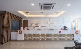 a modern and clean office reception area with white tiles , a wooden counter , and an air conditioner on the ceiling at 906 Premier Hotel
