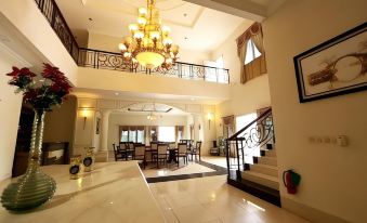 a large , well - lit dining room with multiple tables and chairs , a chandelier hanging from the ceiling , and an open staircase leading to the at Novilla Boutique Resort