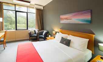 a large bed with a red blanket is in a room with a chair and a window at Frontier Hotel Darwin