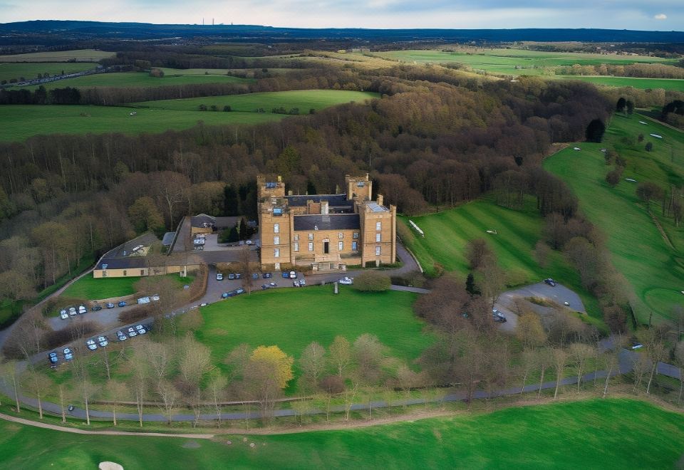 a large building with multiple towers is surrounded by green fields and trees in an aerial view at Lumley Castle Hotel