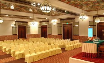a large , well - lit conference room with rows of yellow chairs arranged in front of a long table at Faisalabad Serena Hotel