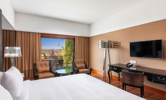 a hotel room with a king - sized bed , a flat - screen tv , and a view of the city at Convento do Espinheiro, Historic Hotel & Spa