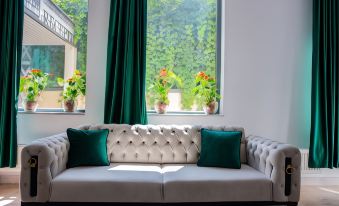 a white couch with green pillows is positioned in front of a window , looking out at a lush garden at Hotel THR Center