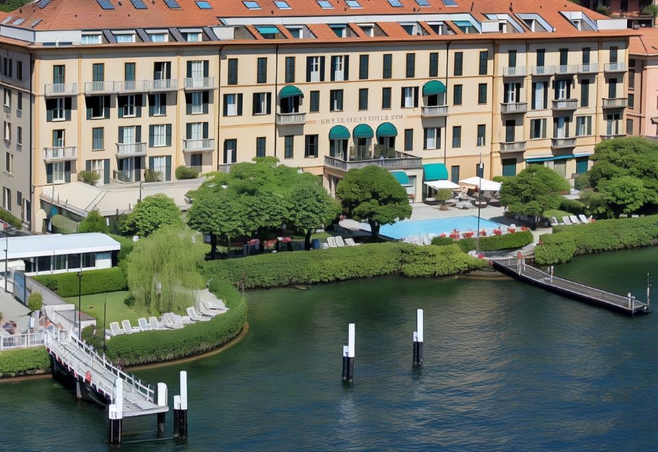 aerial view of a large apartment building surrounded by water , with a dock extending into the lake at Grand Hotel Menaggio