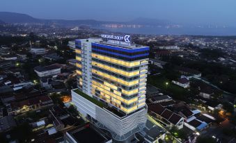 a tall building with a blue and yellow sign on top is illuminated at night at Golden Tulip SpringHill Lampung