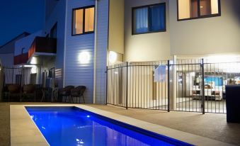 a modern house with a blue swimming pool in the backyard , illuminated by lights at night at Quest Bendigo Central