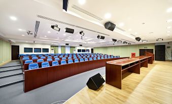 a large , empty conference room with rows of chairs arranged in a semicircle around a podium at Greenwood Hotel