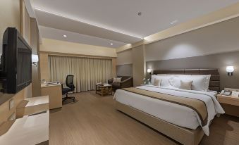 a modern hotel room with a large bed , wooden flooring , and a tv , along with a desk and chair at The Fern Residency Aurangabad
