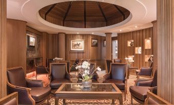 a spacious living room with wooden walls , a round ceiling , and several chairs arranged around a coffee table at Galgorm