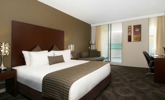 a large bed with a brown headboard and white linens is in a hotel room at Hotel 115