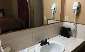a bathroom sink with a white basin and a black faucet , set against a mirror at Camino Real Hotel