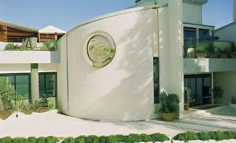 a modern house with a white exterior and a circular emblem on the front is surrounded by greenery at Hotel Astoria