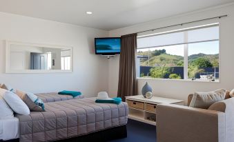 a hotel room with two beds , a desk , and a flat - screen tv mounted on the wall at Motel Oasis