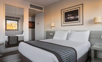 a large bed with white sheets and a black and white patterned blanket is in a hotel room at Exe Salamanca