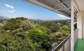 a balcony with a view of the mountains , trees , and houses under a clear blue sky at Murwillumbah Motor Inn