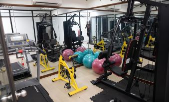 a well - equipped gym with various exercise equipment , including weights and balls , under a large mirror at Jewels Hotel