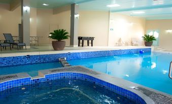a swimming pool with blue tiles , surrounded by a spa area and a game table at Parklands Resort Mudgee